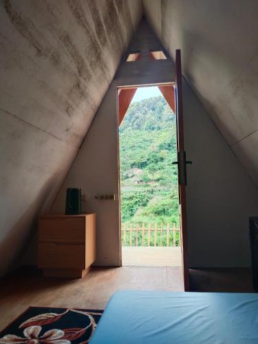a bedroom with a large window in the attic at Cihulu Budget Glamping in Tengahgirang