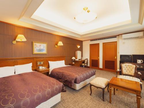 a hotel room with two beds and a desk at Racine Shinmaebashi in Maebashi