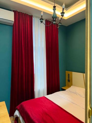 a bedroom with red drapes and a bed with a red bedspread at Three Colour Rooms in Kutaisi