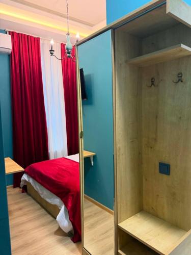 a bedroom with a red bed and a mirror at Three Colour Rooms in Kutaisi