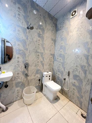 a bathroom with a toilet and a sink and a shower at Hotel Girraj Inn in Vrindāvan