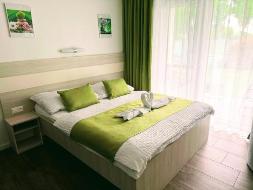 a bedroom with a bed with green sheets and a window at VILLA MEGER in Veľký Meder