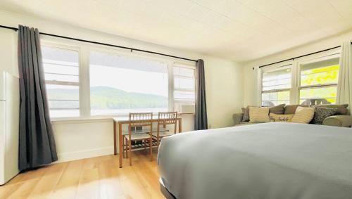 a bedroom with a bed and a table and windows at Motel Luzerne in Lake Luzerne