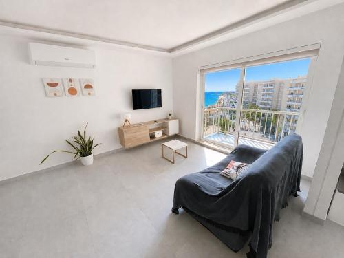 a living room with a couch and a large window at Brand New Seafront Apartment in Sliema