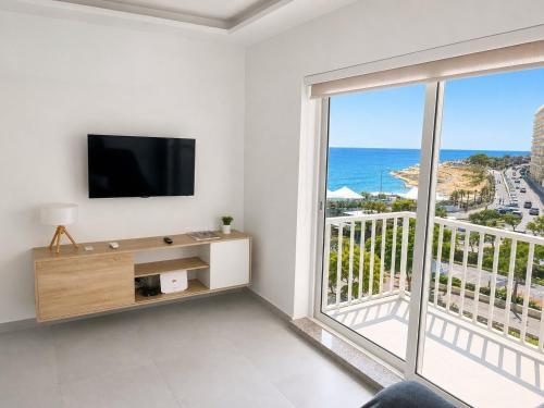 a living room with a tv and a large window at Brand New Seafront Apartment in Sliema