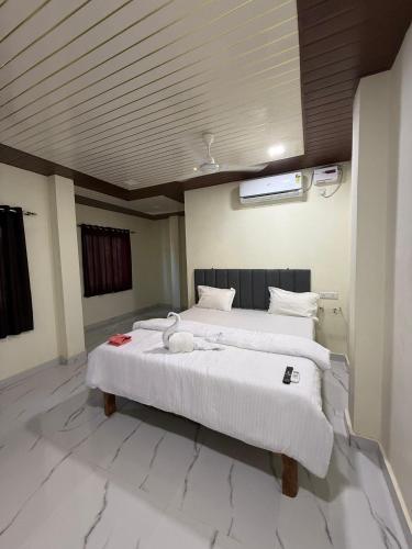 a bedroom with two beds with white sheets at Om residency in Diveagar