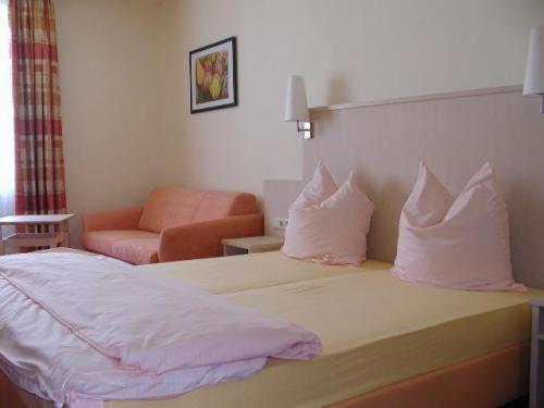 ein Hotelzimmer mit einem Bett mit Kissen und einem Stuhl in der Unterkunft Gasthof zum Brunnen in Mörnsheim