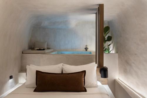 a bedroom with a bed with a mirror over a tub at Agnadema Apartments in Firostefani