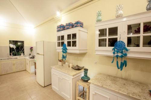 eine Küche mit weißen Schränken und einem Kühlschrank in der Unterkunft Villa Alam Biru Gardenia in Seminyak
