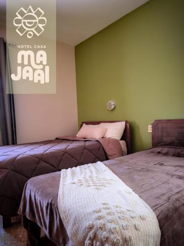 two beds in a room with green walls at Hotel Casa Majaal in Ixtapan de la Sal