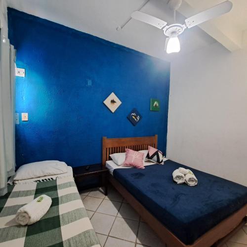 two beds in a room with a blue wall at Pousada Mandala - Búzios in Búzios