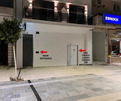 a white building with a door with arrows on it at Nicolas Centrale-Smart City Suites in Igoumenitsa