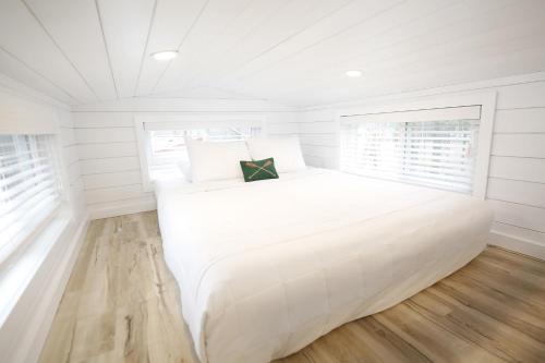a large white bed in a bedroom with white walls at River and Twine in Rocky Mount