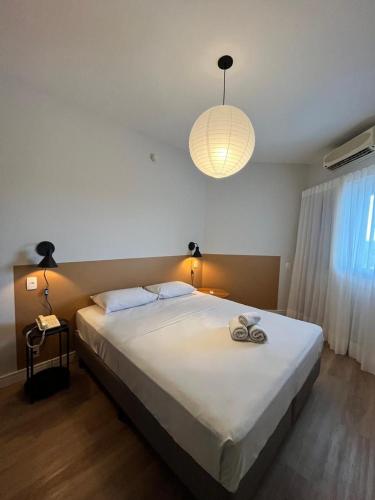 a bedroom with a large white bed with a light at Summit Flat São José dos Campos in São José dos Campos
