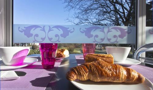een tafel met een bord croissants en kopjes en een raam bij Tourhotel Blois in La Chaussée-Saint-Victor
