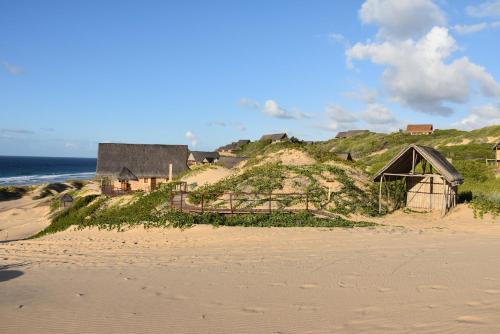 a beach with houses on a hill next to the ocean at Khumbula iMozambique in Inhambane