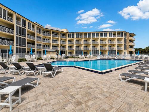 a resort with a swimming pool and lounge chairs at Ocean East Resort Club in Ormond Beach