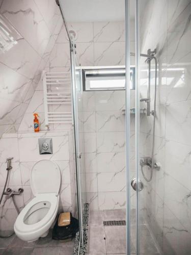 a white bathroom with a toilet and a shower at Flora-A in Chakvi