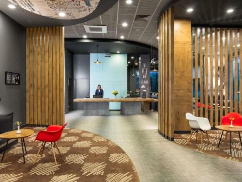 a lobby with red chairs and tables and a counter at Ibis Istanbul Tuzla in Tuzla