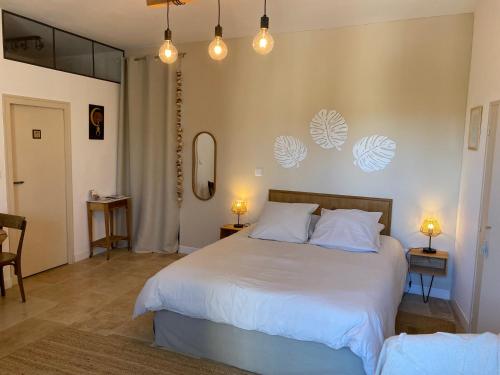 a bedroom with a large white bed with two lamps at Le mas de Marie in Taulignan