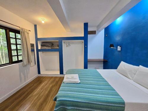 a bedroom with a bed with a blue wall at Casa Amarela, Refúgio na natureza Rota do vinho in São Roque