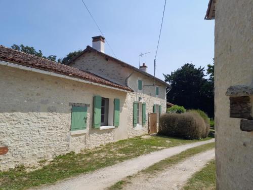 a building with green shutters and a dirt road at Maison Brunetière in Saint-Martin-lʼArs