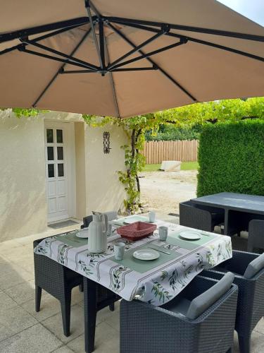 a table and chairs under an umbrella on a patio at Maison Brunetière in Saint-Martin-lʼArs