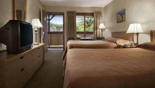 a hotel room with two beds and a flat screen tv at Magnuson Grand Rushmore View in Keystone
