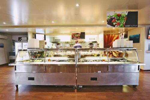 Un mostrador de comida en un restaurante con gente preparando comida. en Capricorn Village, en Newman