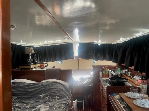 a room with a bed and a kitchen with black curtains at Eco Yacht Charters in Almere