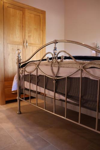 a metal bed in a room with a wooden cabinet at South Barn in Stanningfield