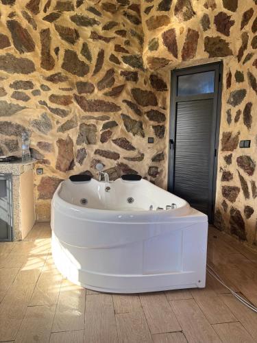 a white bath tub sitting in a room with a stone wall at Chalet en Pierre Benslimane in Aïn Sferjila