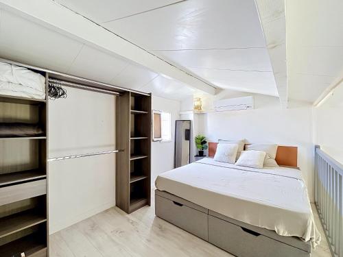 a white bedroom with a bed and a refrigerator at Maison village accès mer et commerces à pieds in Le Barcarès