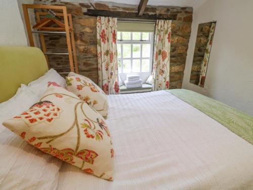 a bedroom with a white bed with pillows and a window at May Cottage in Pentewan