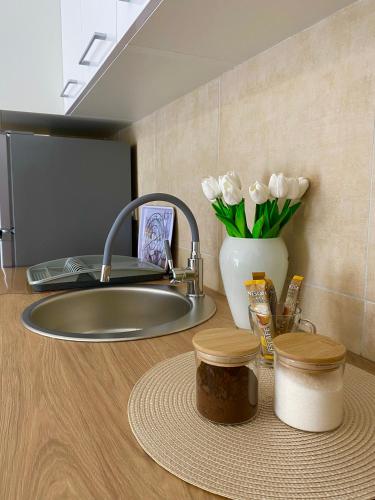 a kitchen counter with a sink and a vase of white flowers at Verde Apartment in Banja Luka