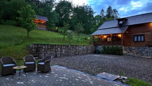 a house with a stone wall and chairs and a table at Cabana Codrii Maramuresului in Giuleşti