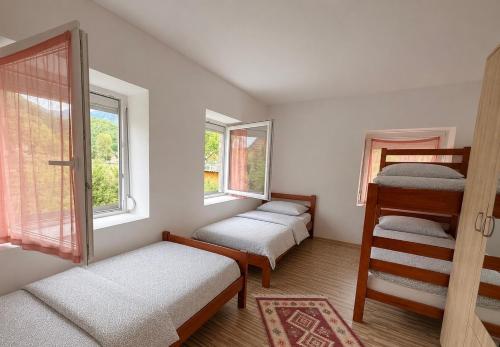 a room with two bunk beds and two windows at Blue Eye in Vusanje