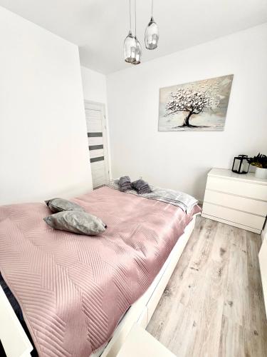 a white bedroom with a bed and a wooden floor at Apartament Tosia in Chełm
