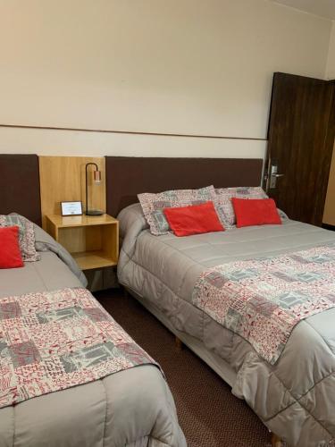 two beds in a room with red pillows on them at Hotel Los Condores in Uspallata