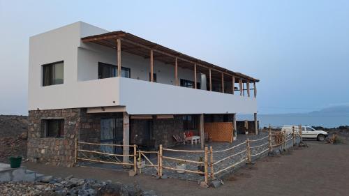 a white building with a fence in front of it at Kasa surf in Porto Novo