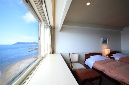 函館市にある函館 湯の川 平成館しおさい亭のベッド2台、海の景色を望む窓が備わる客室です。