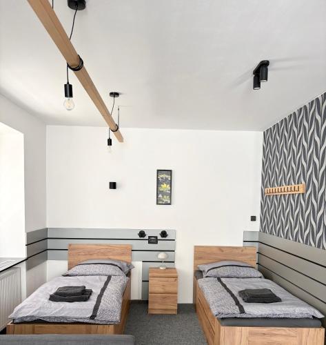 two beds in a room with white walls at Apartmán Majerův dvůr in Rožnov pod Radhoštěm