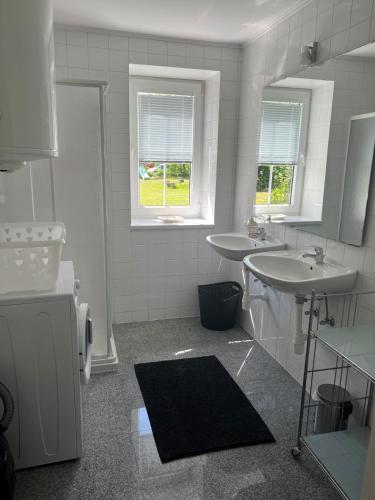 a white bathroom with two sinks and two windows at Karawanken Glück in Feistritz im Rosental