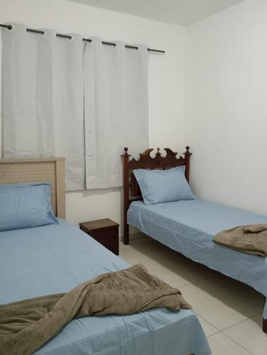 a bedroom with two beds with blue sheets at Recanto Tarobá in Ponta Grossa