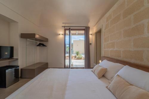 a bedroom with a white bed and a brick wall at Setteminne Resort Design in Favignana