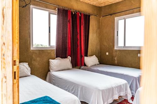 two beds in a room with two windows at Gite Skoura in Caïd Bou Malla