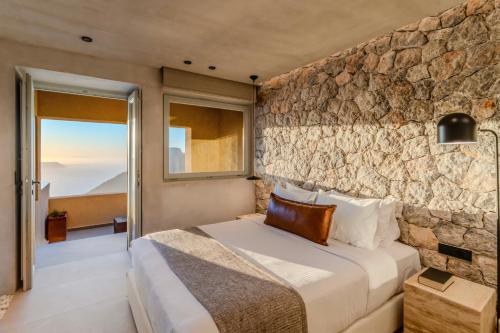 a bedroom with a stone wall at Agnadema Apartments in Firostefani