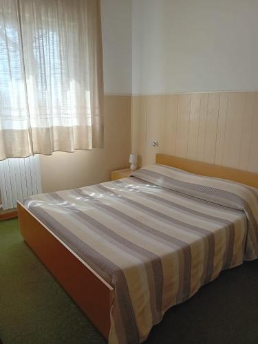 ein großes Bett in einem Zimmer mit Fenster in der Unterkunft Hotel Cucciolo in Donoratico