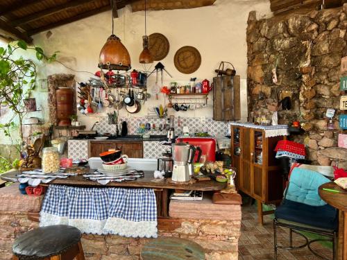 a kitchen with a wooden table and a counter top at CASA DE RETALHOS Boutique Albergue, casaril histórico, com 5 suítes individuais e cozinha coletiva, no coração da vila de Igatu-Ba, que preserva fortes traços culturais da época do garimpo, venha viver uma experiência única! in Igatu