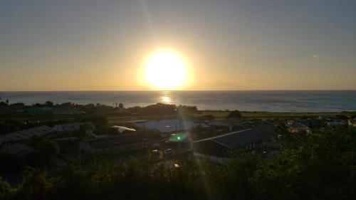 a sunset over the ocean with the sun in the sky at sunset lovers cottage in Canefield